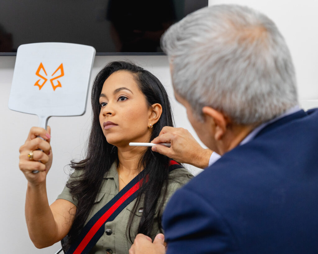 Patient reviewing facial profile in a mirror during a consultation with a North Miami plastic surgeon.