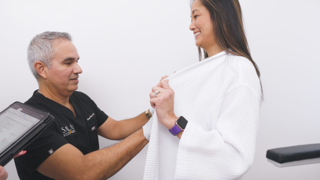 A plastic surgeon assesses a patient's breasts to plan for a breast lift near Fort Lauderdale.